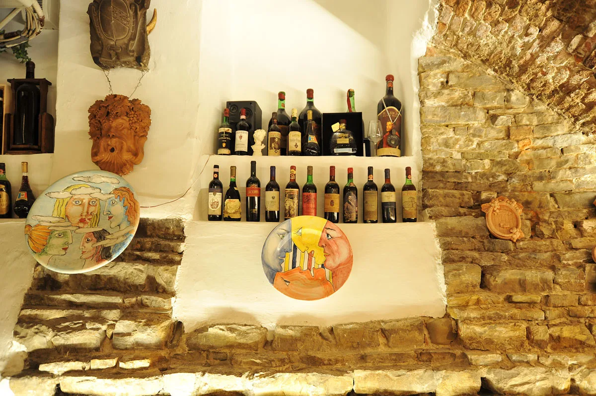 Vini e piatti decorati sulle pareti in pietra della cantina