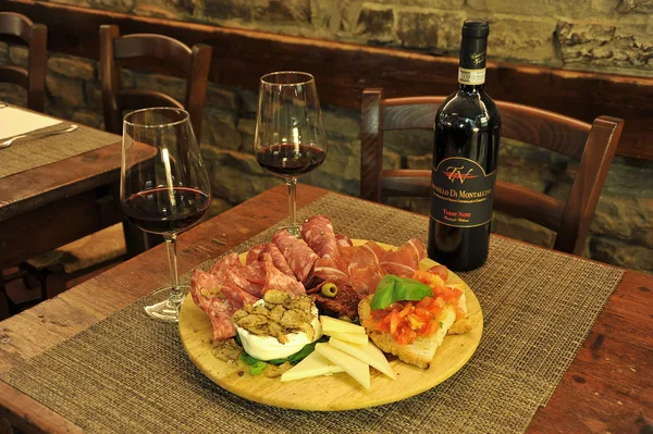 Salumi, formaggi e crostini con un rosso di Montalcino.